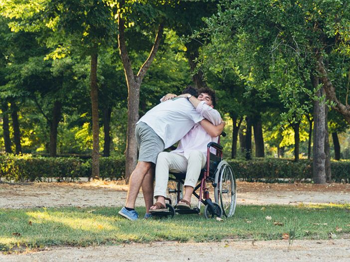Un joven abraza a otro en silla de ruedas