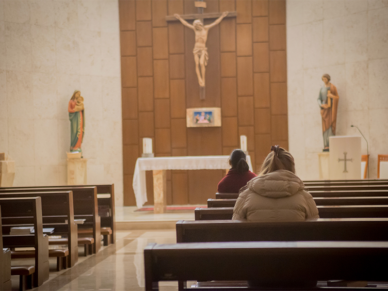 Dos personas rezando en una parroquia