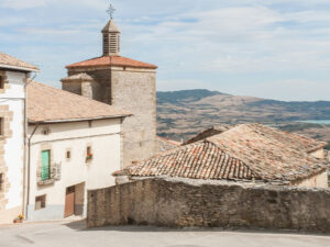 Paisaje rural, con una casa, una iglesia y montañas