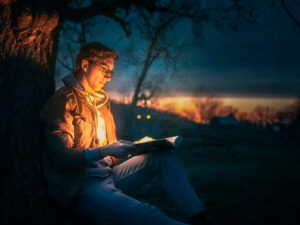 Un hombre leyendo apoyado en un árbol
