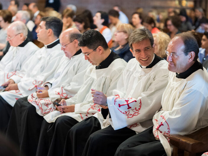 Un sacerdote sonríe a otro durante una ordenación sacerdotal