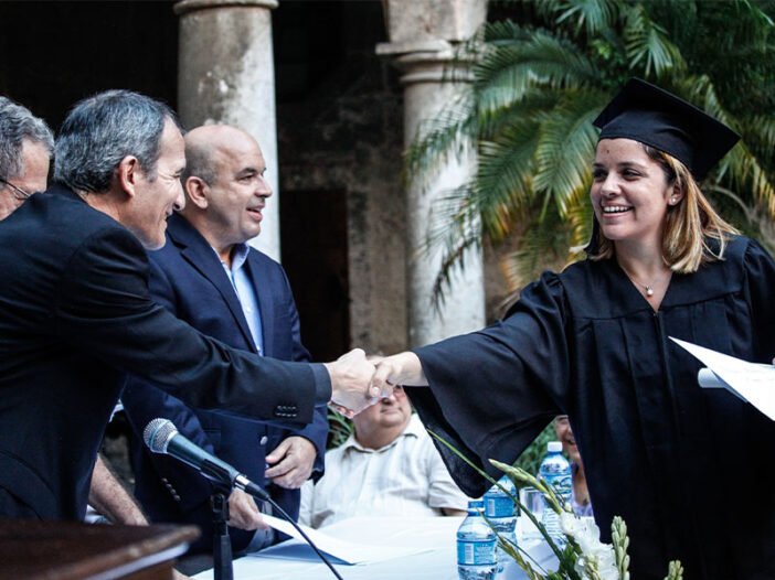 Una estudiante universitaria saludando a varios profesores en su acto de graduación