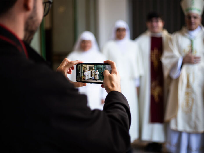 Una persona fotografía a un grupo de monjas, un sacerdote y un obispo